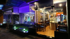 A modern restaurant with glass walls, a seating area with tables and chairs, and a Coca-Cola refrigerator. - Hotel Eurolanka Colombo (Colombo)