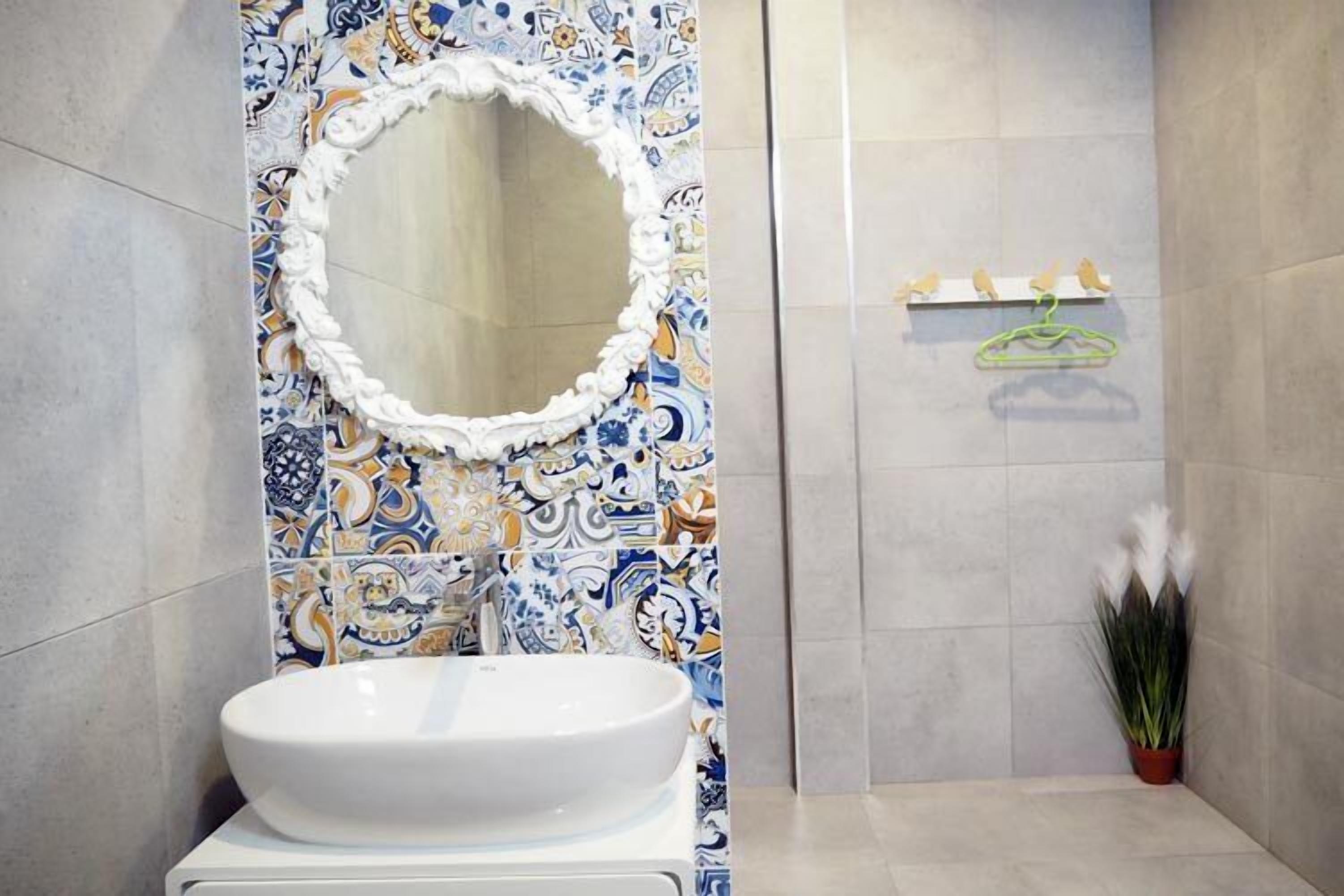 Une salle de bain avec un lavabo blanc, un miroir décoratif et un espace douche.