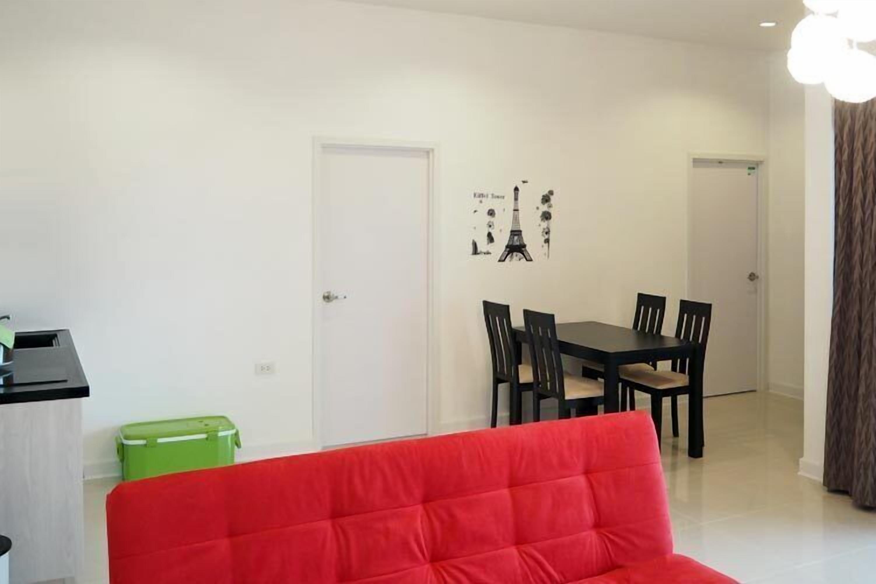 A modern living room with a red sofa, a dining area with a table and chairs, and a green storage box.