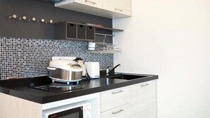 A modern kitchen with a black countertop, white cabinets, and a tiled backsplash. - Le Leaf Pool Villa 7 (Hua Hin)