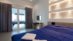 A modern hotel room with a large bed, a desk, and a sliding glass door leading to a balcony. - Le Leaf Pool Villa 7 (Hua Hin)