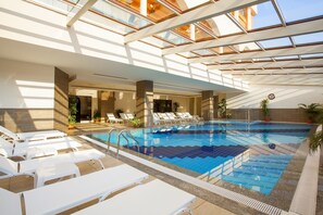 Een binnenzwembad, een buitenzwembad en parasols bij het zwembad