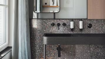 Un bagno moderno con un piano in granito, uno specchio e un lavabo con più rubinetti.