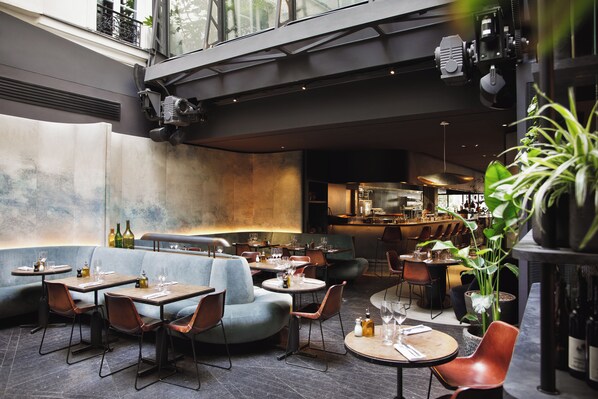 Un comedor interior con cabinas y mesas, una zona de bar y una cocina al fondo.