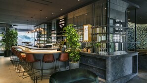 Een moderne bar met een gebogen toonbank, barstoelen en potplanten.