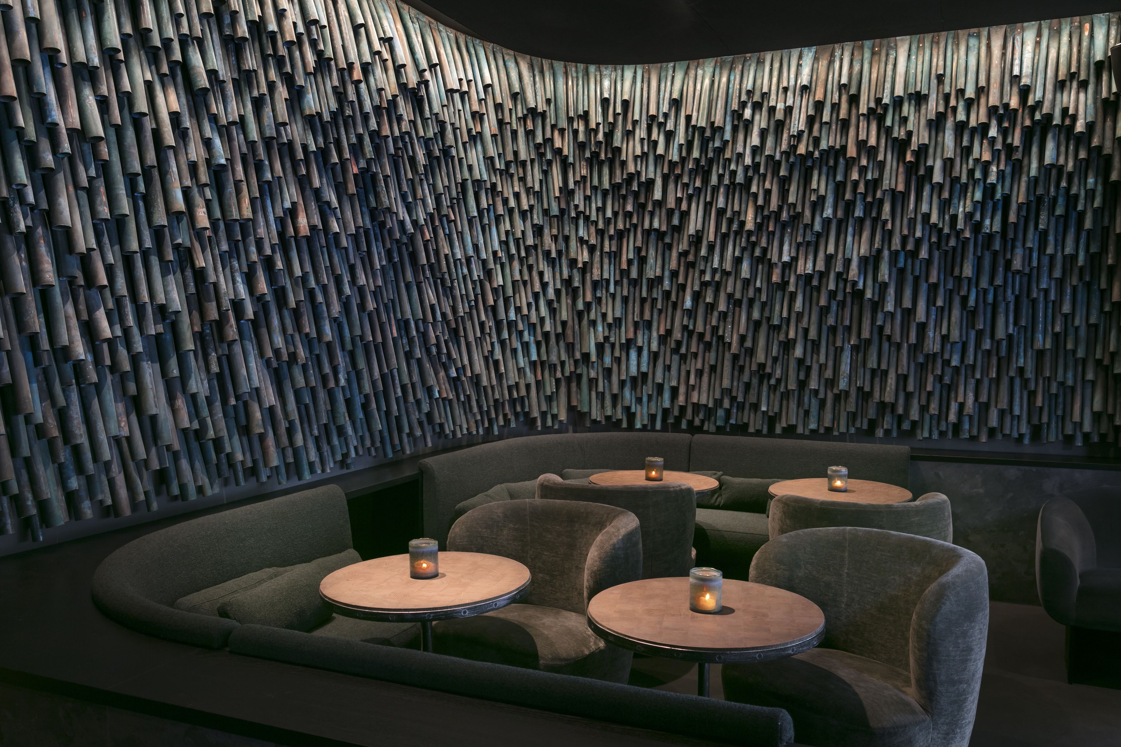 A modern interior with a unique acoustic panel wall, comfortable seating, and small tables with candles.
