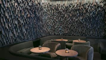 A modern interior with a unique acoustic panel wall, comfortable seating, and small tables with candles.