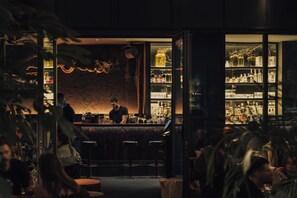 Una zona de bar con un cantinero, estantes llenos de botellas y una pared decorativa.