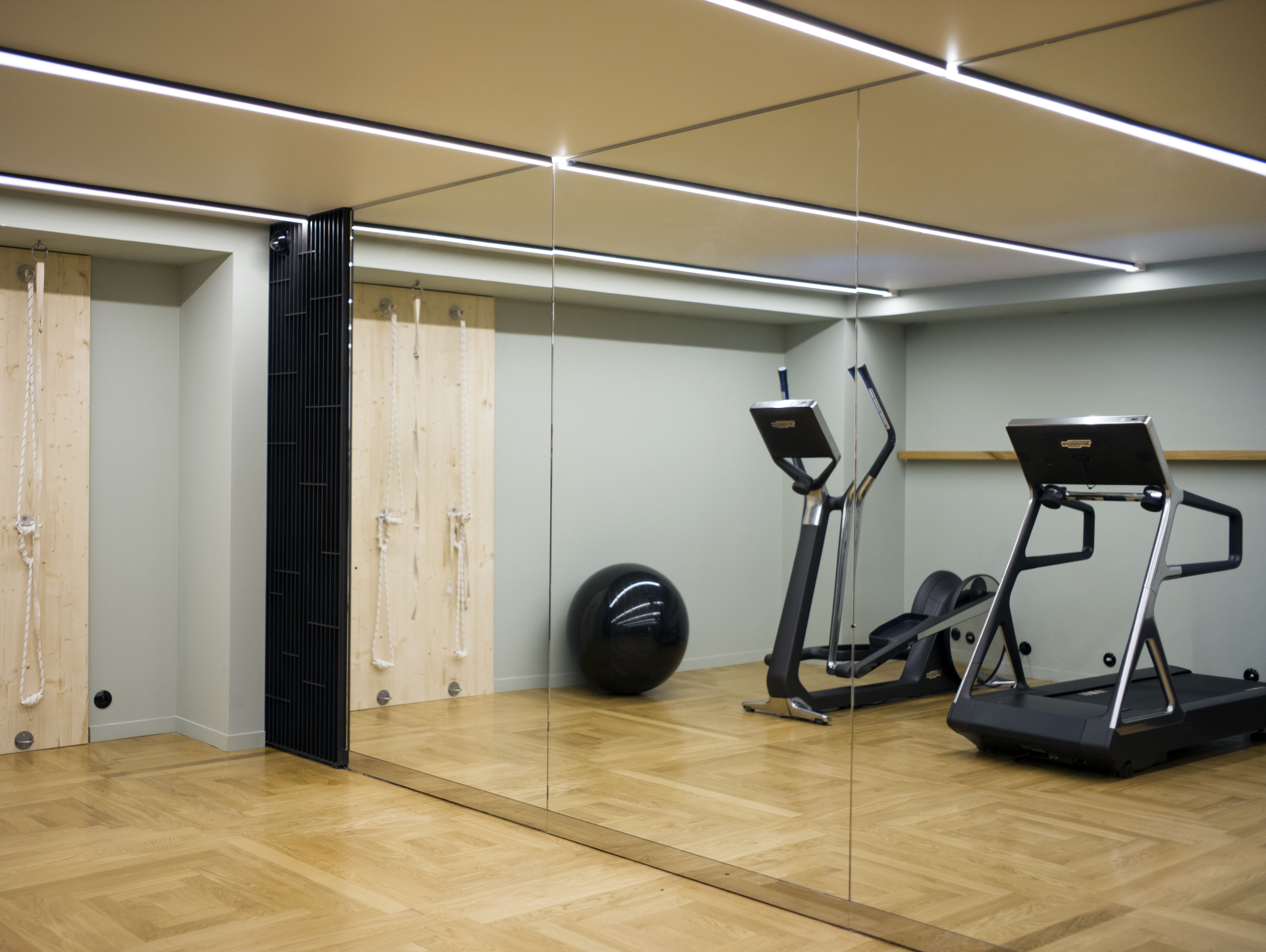 Una palestra con attrezzi da ginnastica, uno specchio e un pavimento in legno.