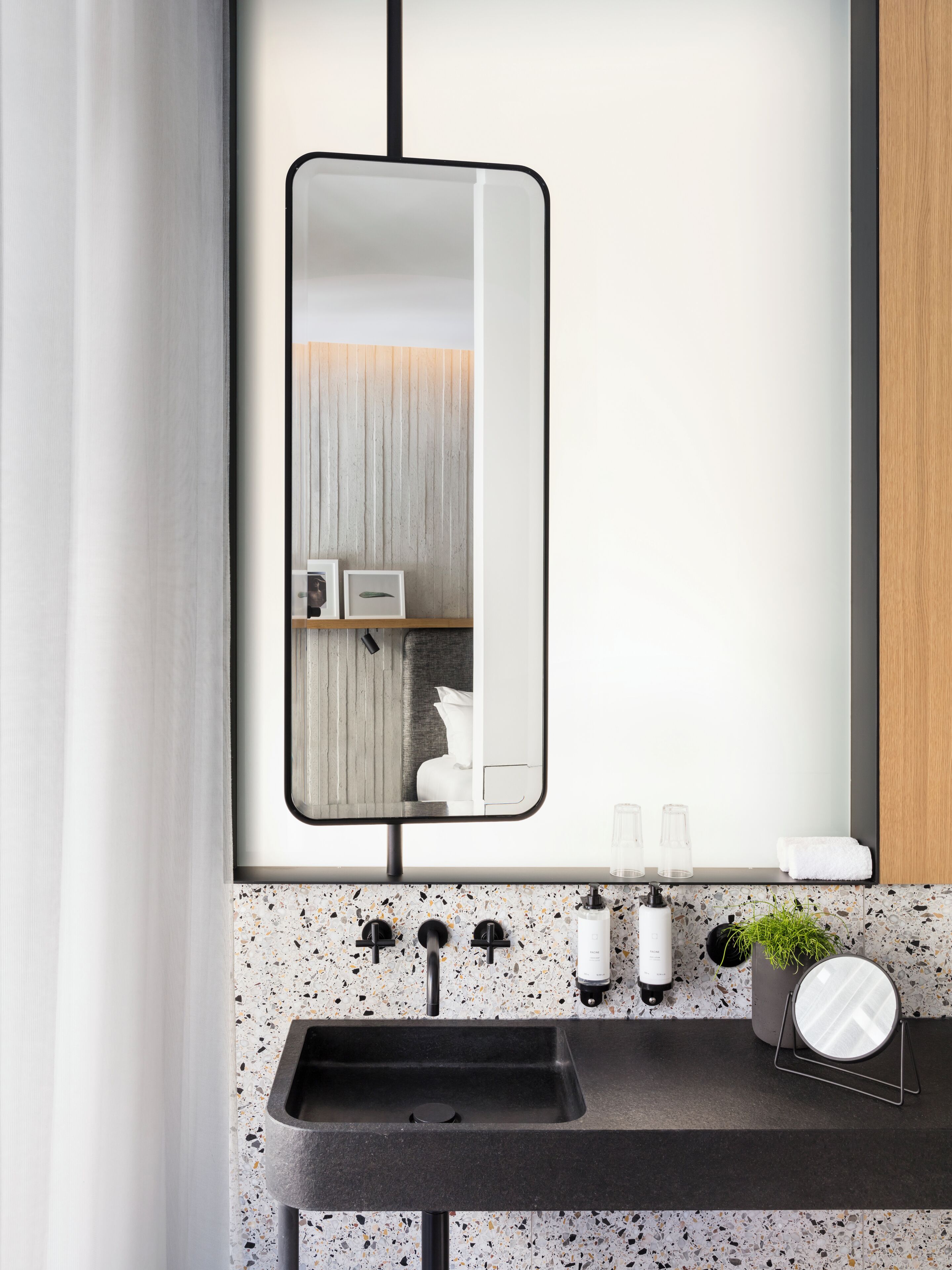 A modern bathroom with a large mirror, a granite countertop, and a sink.