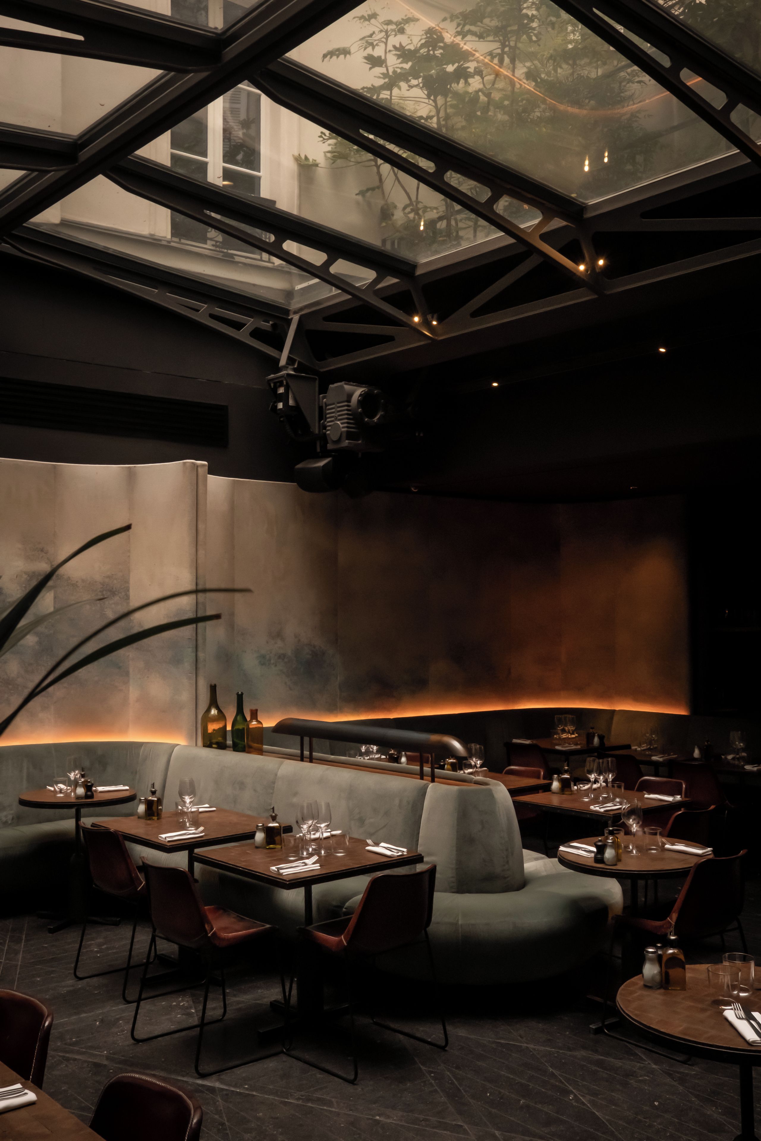 A restaurant interior with a high ceiling, modern furniture, and a view through a large window.