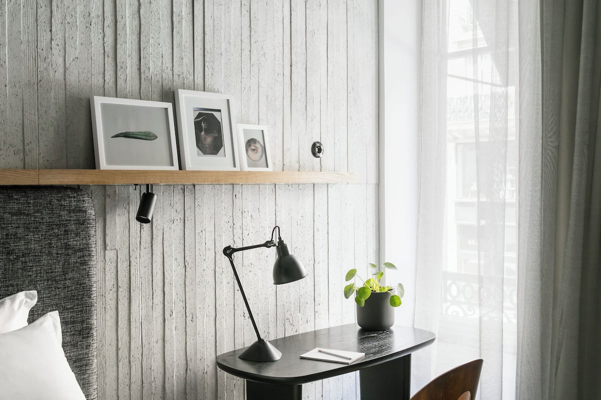 Un dormitorio moderno con un revestimiento de madera, una mesita de noche con lámpara, una silla y una cama.