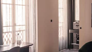 A hotel room with a bed, a desk, and a chair. There is a bathroom visible through an open door.