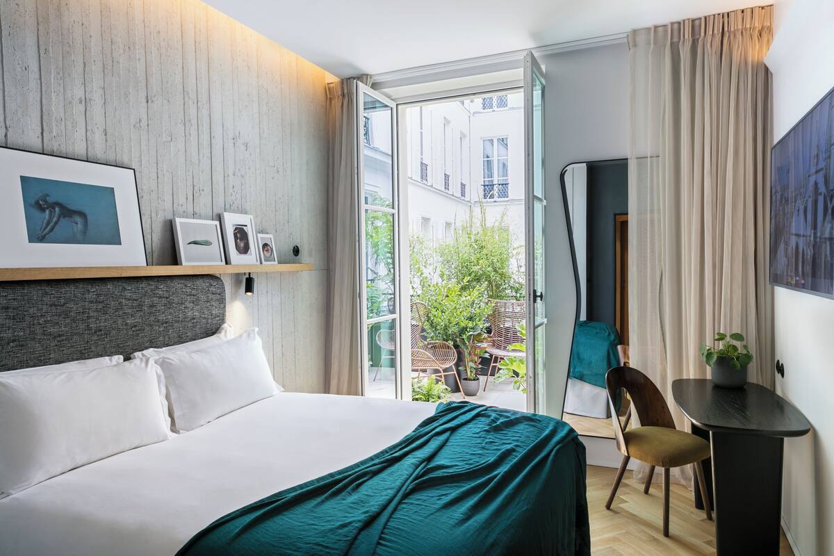 Una habitación de hotel moderna con una cama grande, un escritorio y vistas a la ciudad.