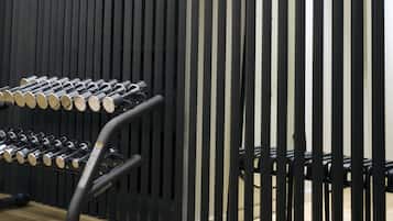 A gym with a wall of vertical black slats and a rack of dumbbells.