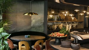 Een moderne eetruimte met een ronde tafel, lederen stoelen en een centraal kookeiland met een schaal fruit.