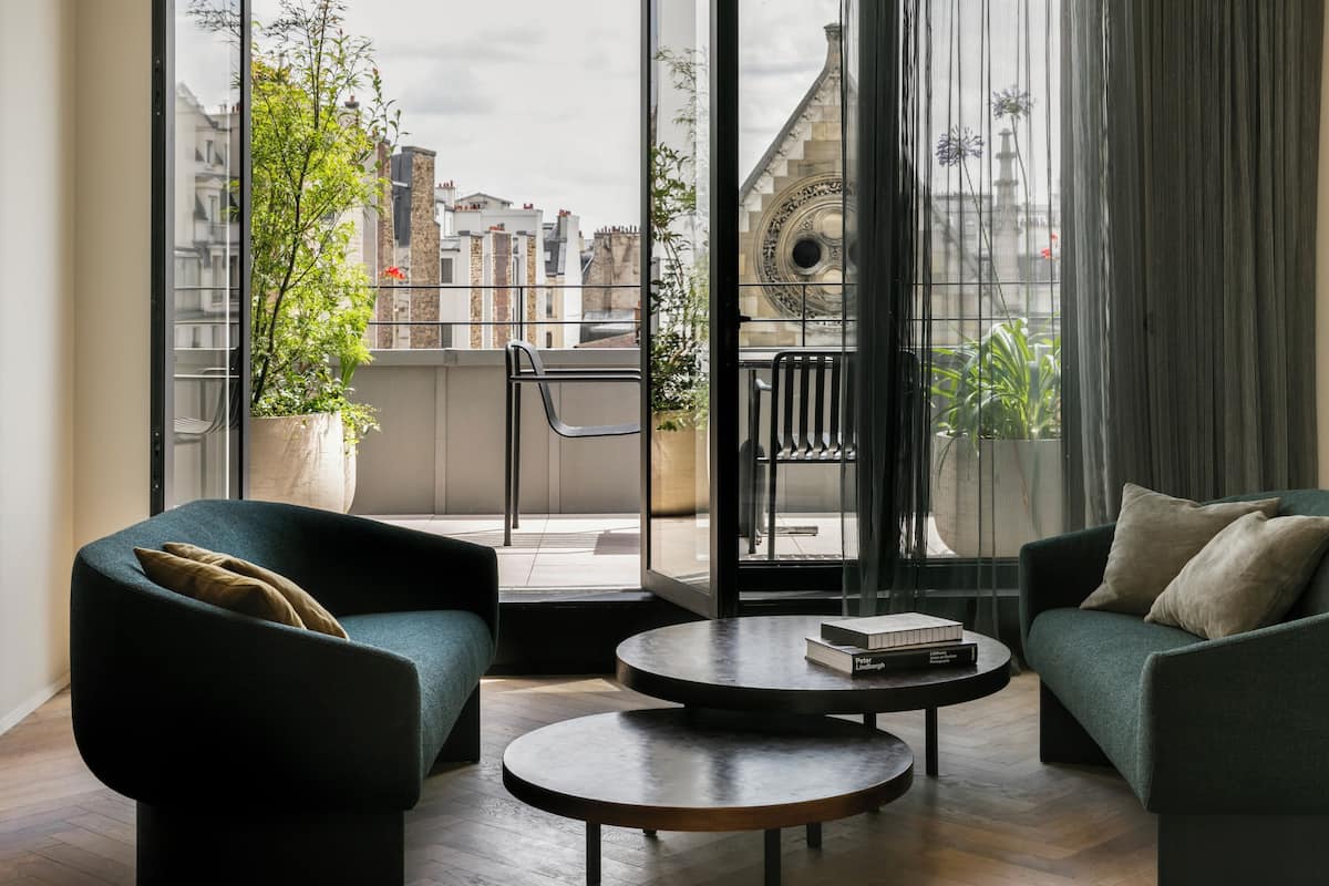 Un salón moderno con dos sofás, una mesa de centro y un ventanal con vistas a edificios y una torre del reloj.