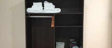 Un armario de madera oscura con varios estantes, una sección para colgar ropa y un zapatero en la parte inferior.