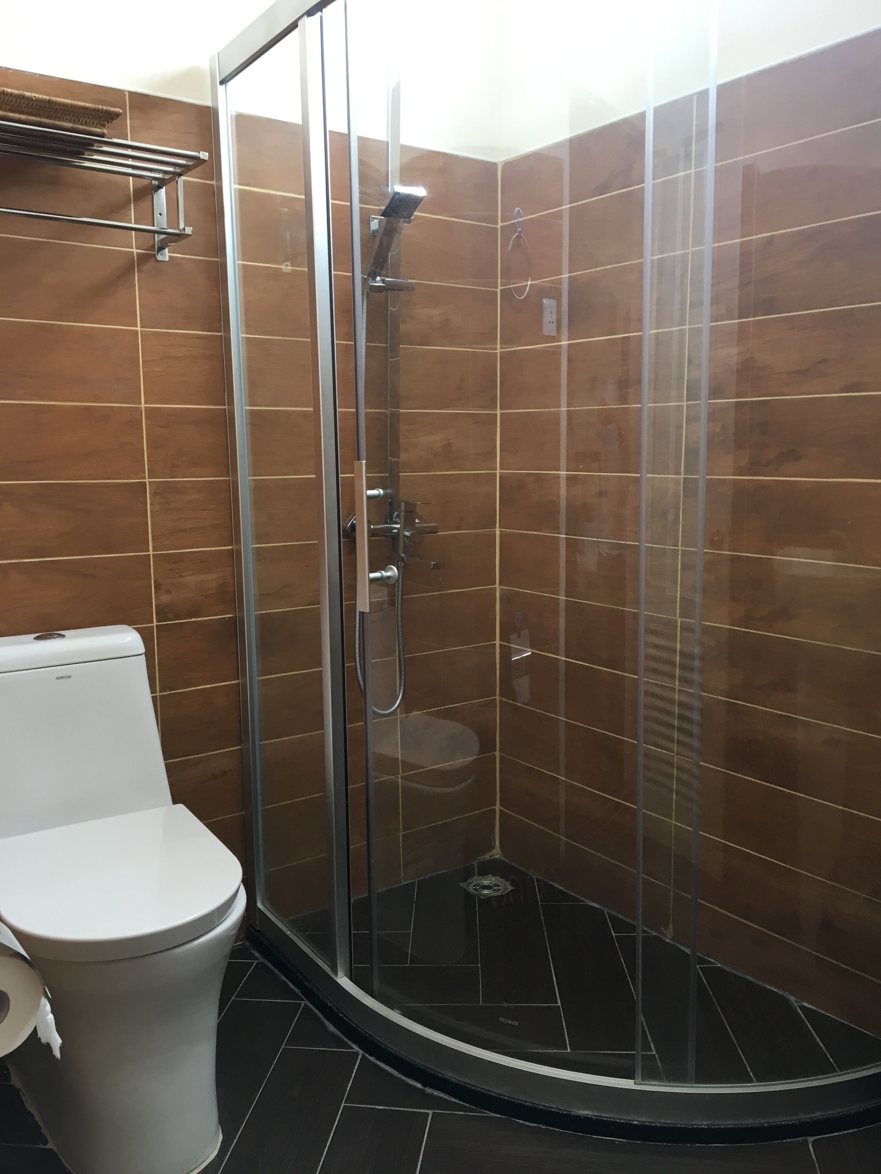 Un baño moderno con ducha de vidrio, inodoro y toallero.