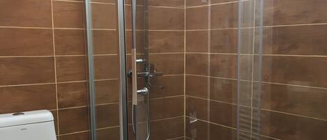 Un baño moderno con ducha de vidrio, inodoro y toallero.