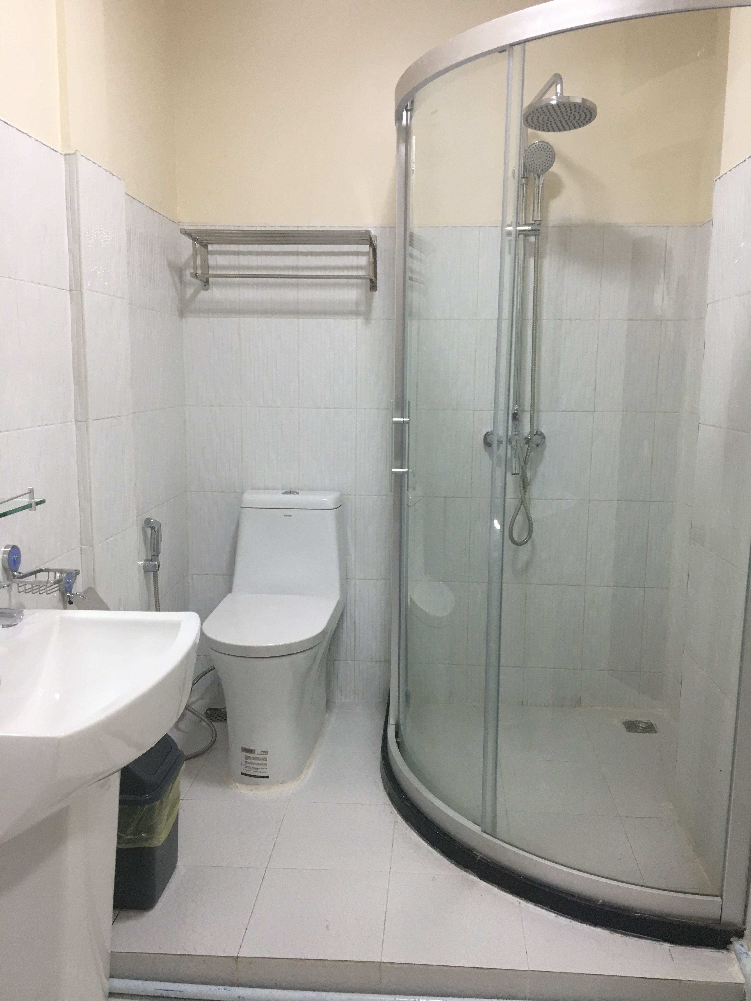 A bathroom with a glass-enclosed shower, a toilet, and a sink.