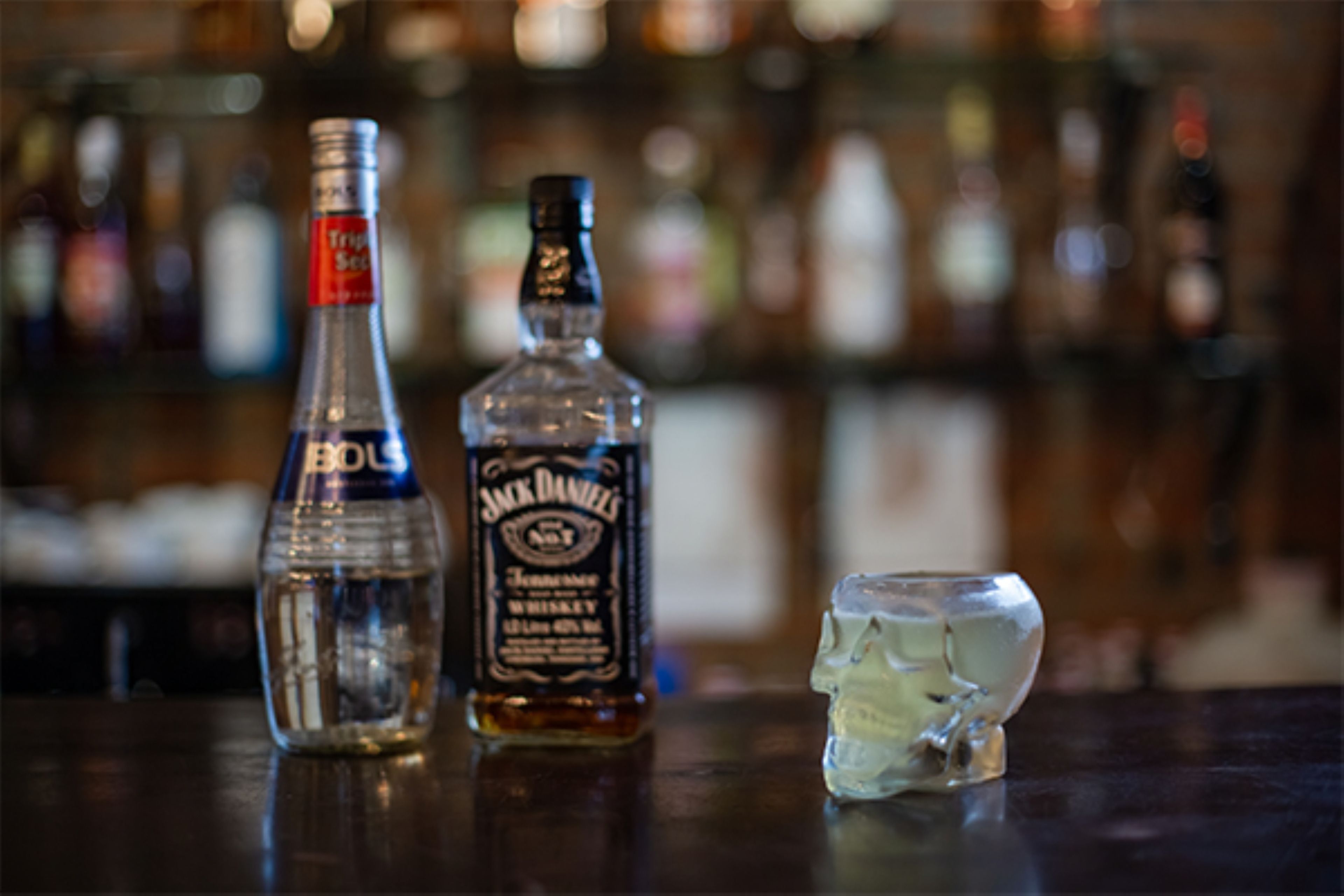 Un bar con botellas de licores y una copa.