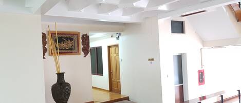 Un pasillo amplio con un banco de madera, un jarrón decorativo y una obra de arte enmarcada en la pared.