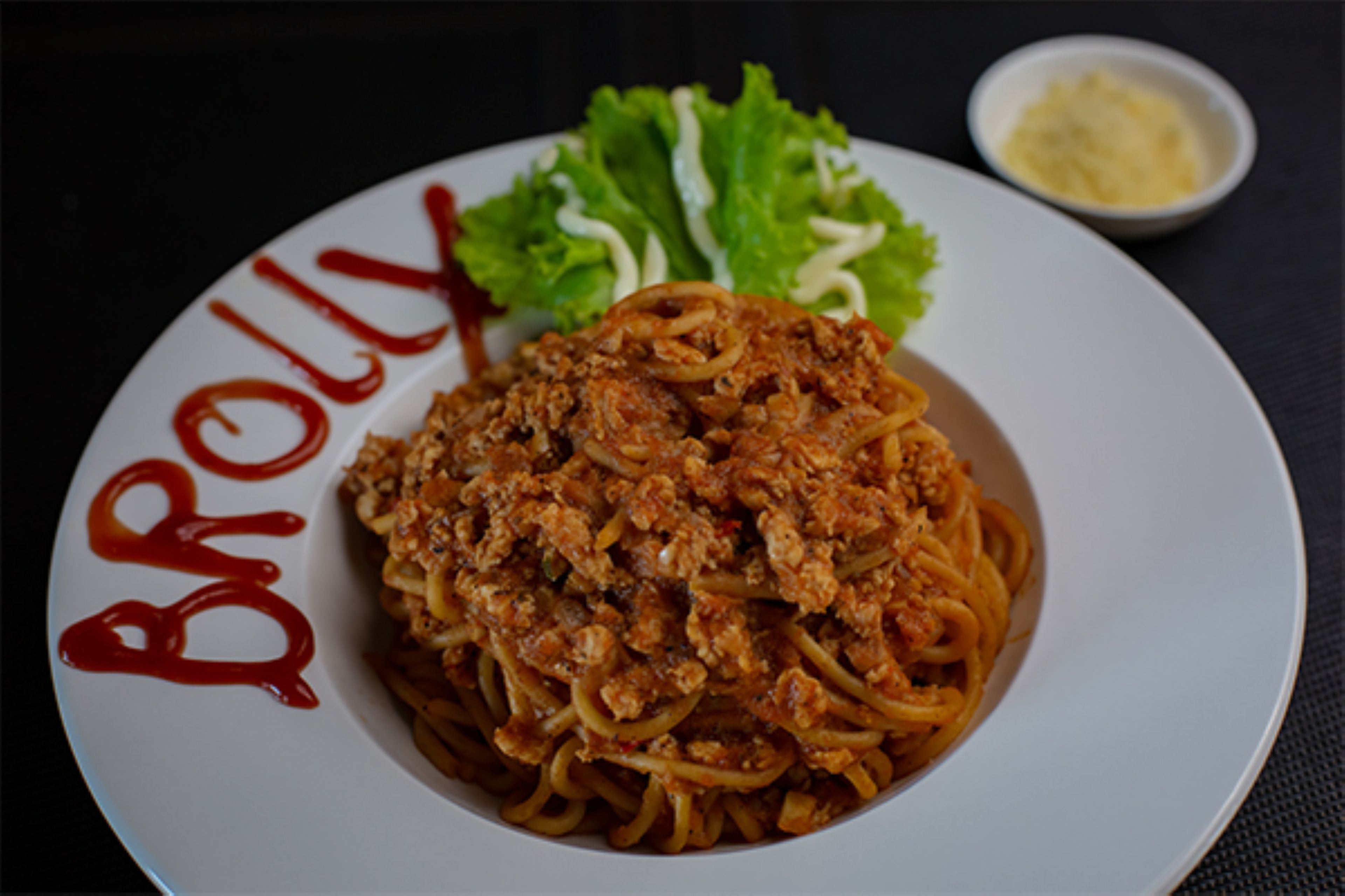 Un plato de espagueti con salsa de carne y una guarnición de lechuga.