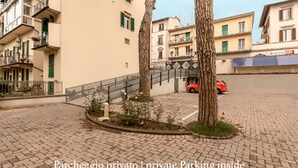 A private parking area with a paved surface, surrounded by buildings with balconies and green shutters. - Gourmet B&B Villa Landucci (Florence)
