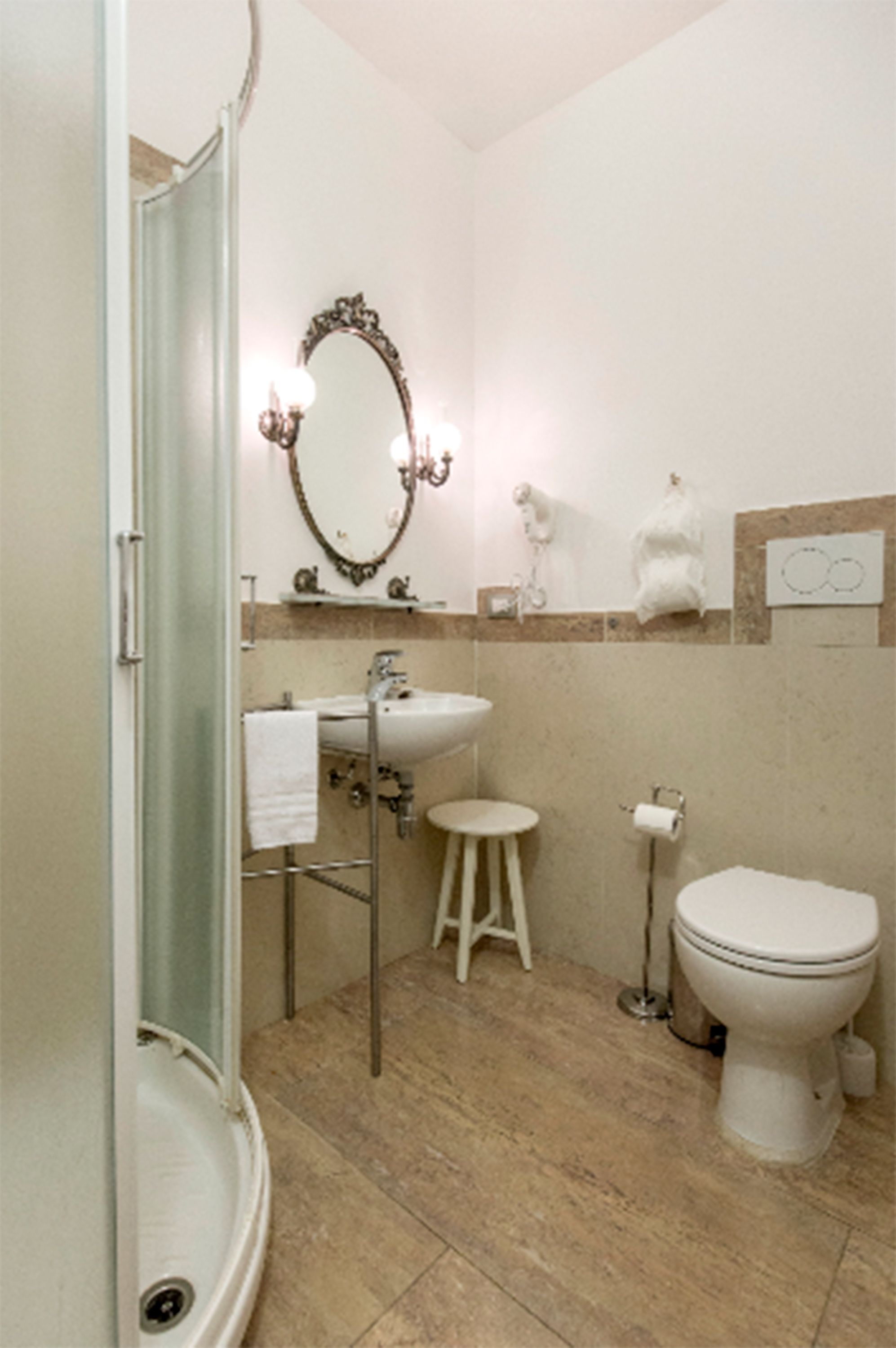 A bathroom with a glass-enclosed shower, a sink with a vanity, a toilet, and a decorative mirror.