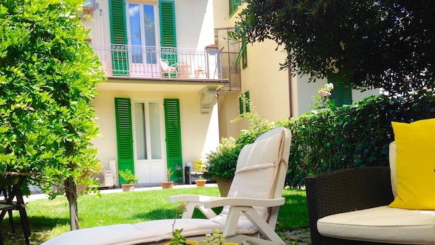 A glass-top table with a white chair and a yellow cushion, surrounded by potted plants. - Gourmet B&B Villa Landucci (Florence)