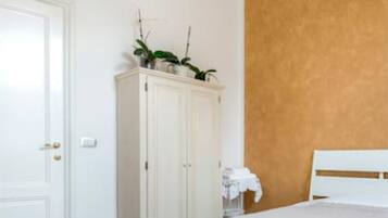 A bedroom with a white bed, a white wardrobe, and a wooden accent wall.