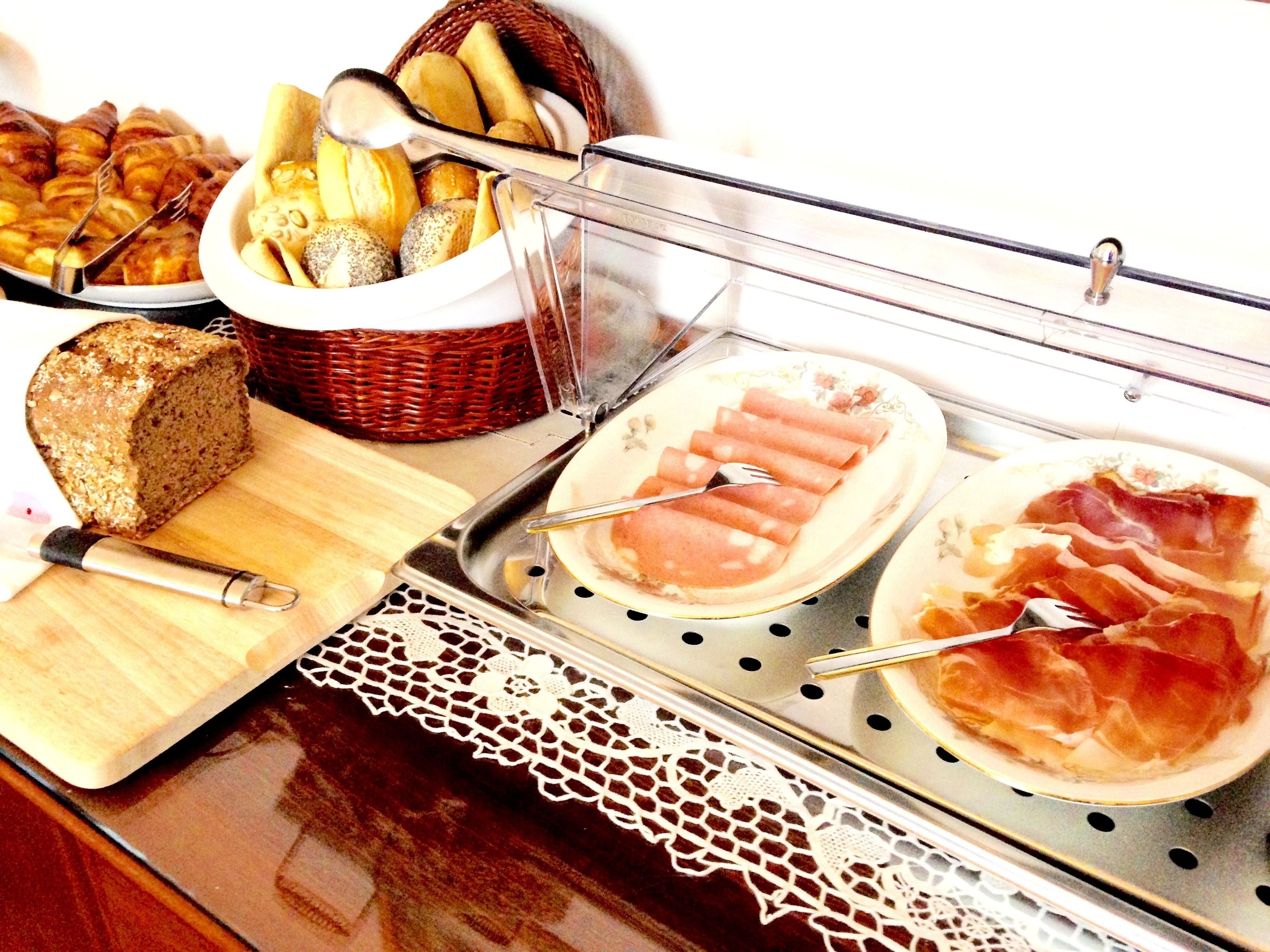 Un buffet proposant une variété de plats, notamment du pain, des pâtisseries et des viandes en tranches.