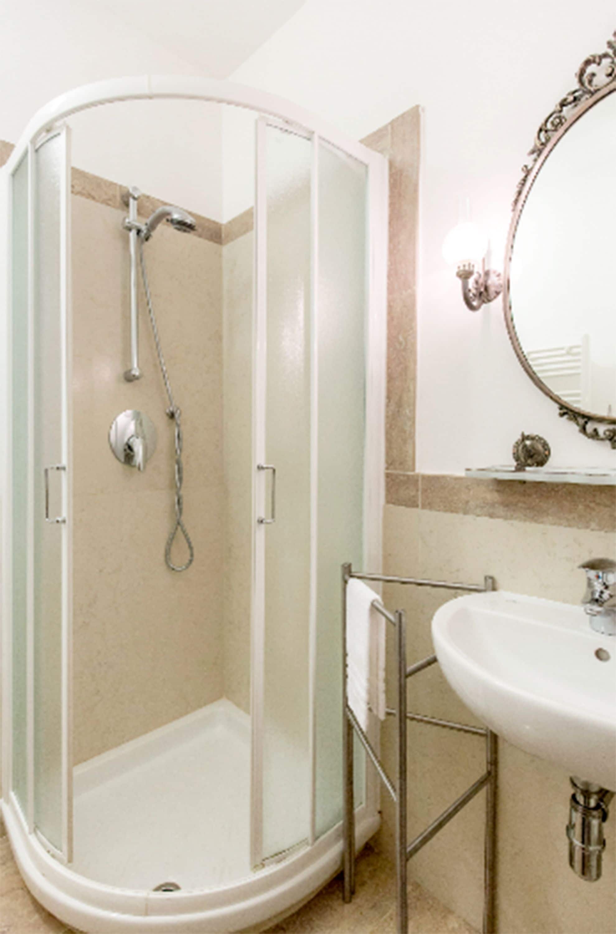 Ein Badezimmer mit Duschkabine, Waschbecken und Spiegel.