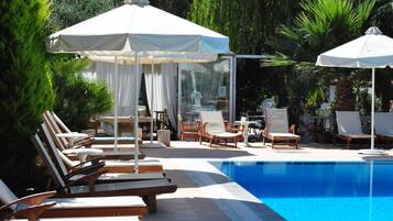 Alberca al aire libre, sombrillas en la alberca y camastros