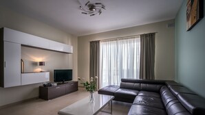 A modern living room with a sofa, TV, and a coffee table. - Consiglia Apartments - Sliema (Sliema)