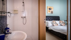 A modern bathroom with a white sink, a glass shower enclosure, and a black bathtub. - Consiglia Apartments - Sliema (Sliema)