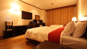 A hotel room with a large bed, a desk with a computer, a flat-screen TV mounted on the wall, and a water dispenser. - King Hotel (Seongnam)