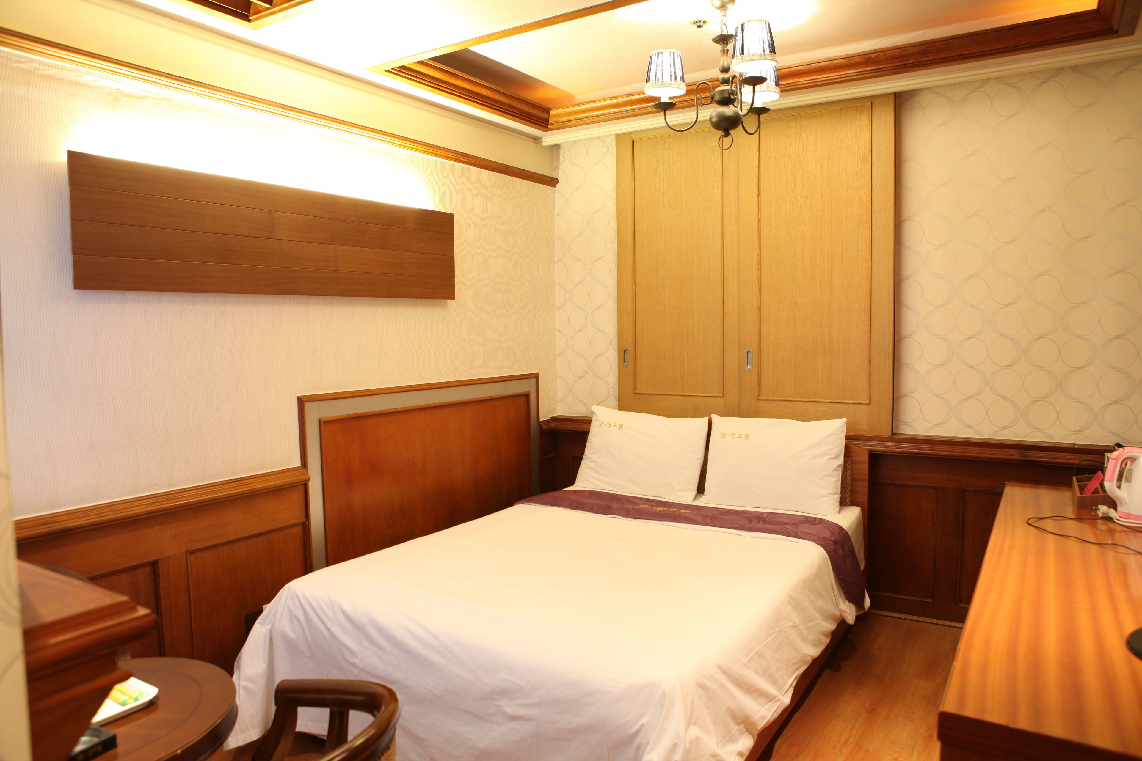 Una habitación de hotel con una cama de madera, un escritorio y un armario.
