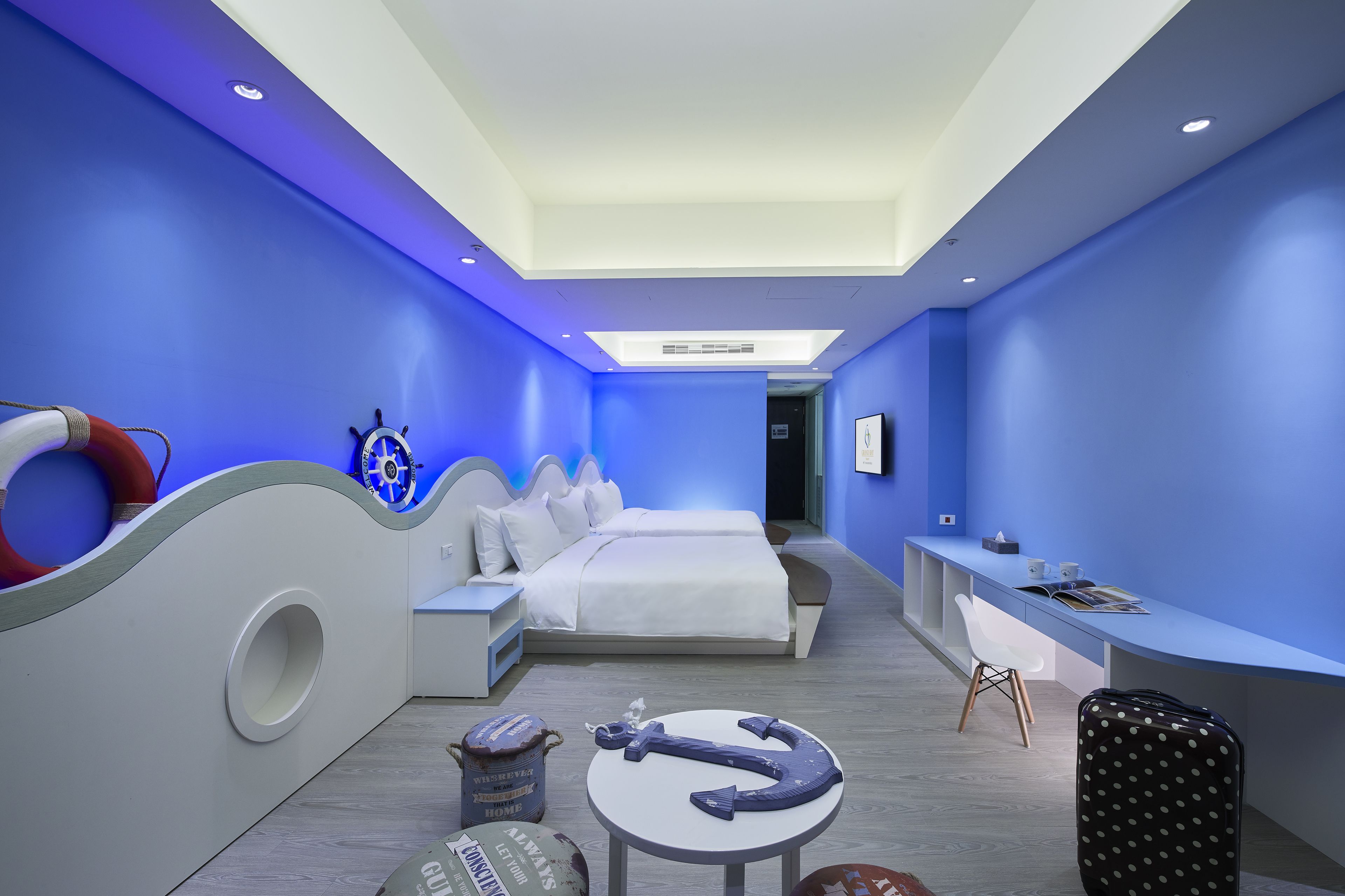 A modern hotel room with a bed, desk, and seating area.