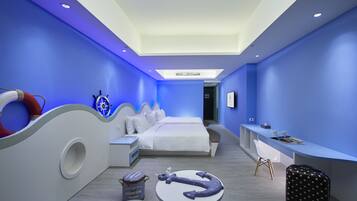 A modern hotel room with a bed, desk, and seating area.