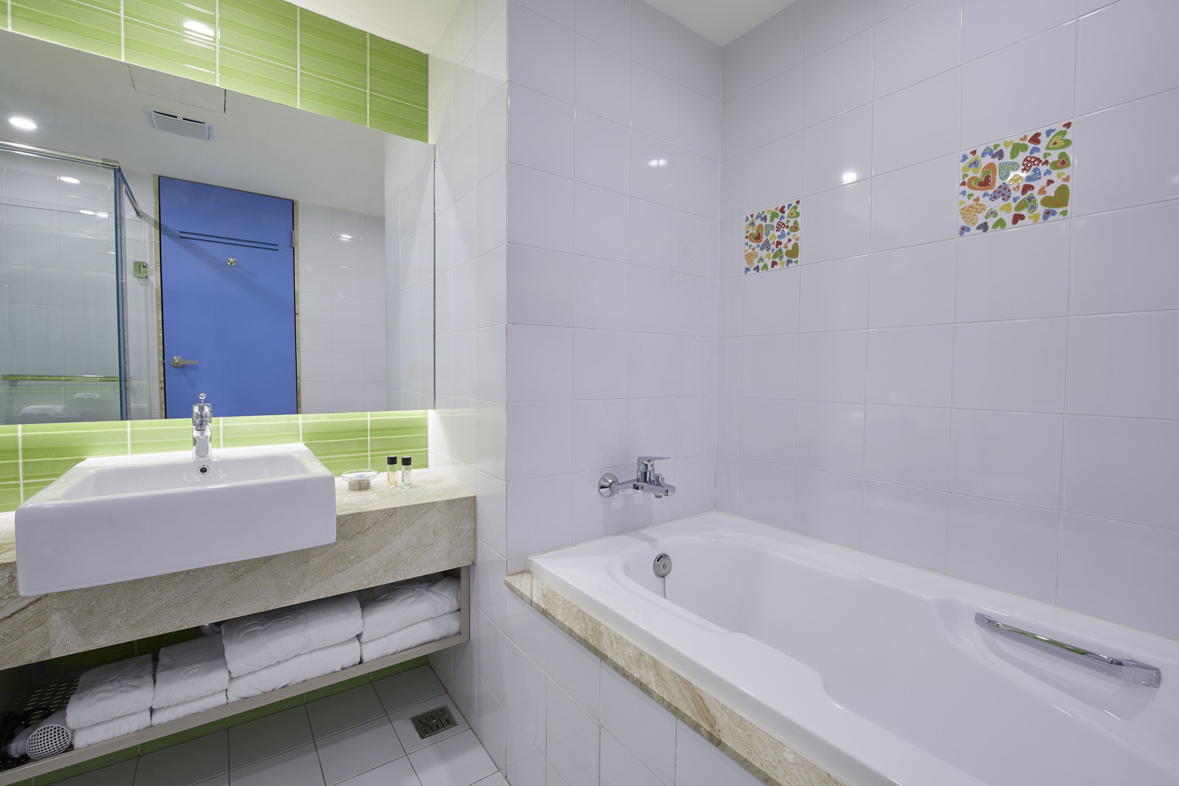 Une salle de bain moderne avec un lavabo blanc, une baignoire et une porte bleue.