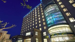 A modern hotel with a curved glass facade, multiple floors, and a central atrium. - Grand Bay Resort (Hengchun)