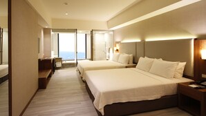 A hotel room with two beds, a sitting area with a view, and a large mirror. - Grand Bay Resort (Hengchun)