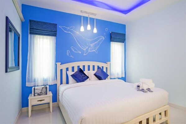 Un dormitorio con cama, mesita de noche, un mural en la pared y una lámpara en el techo.