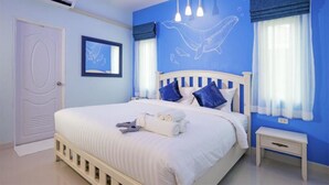 A bedroom with a bed, bedside table, and a wall with a dolphin mural. - Aonang Sweet Blue Sea (Krabi)