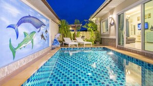 A swimming pool with a tiled floor, a mural of a whale and dolphins, and a patio area with lounge chairs and a pergola. - Aonang Sweet Blue Sea (Krabi)
