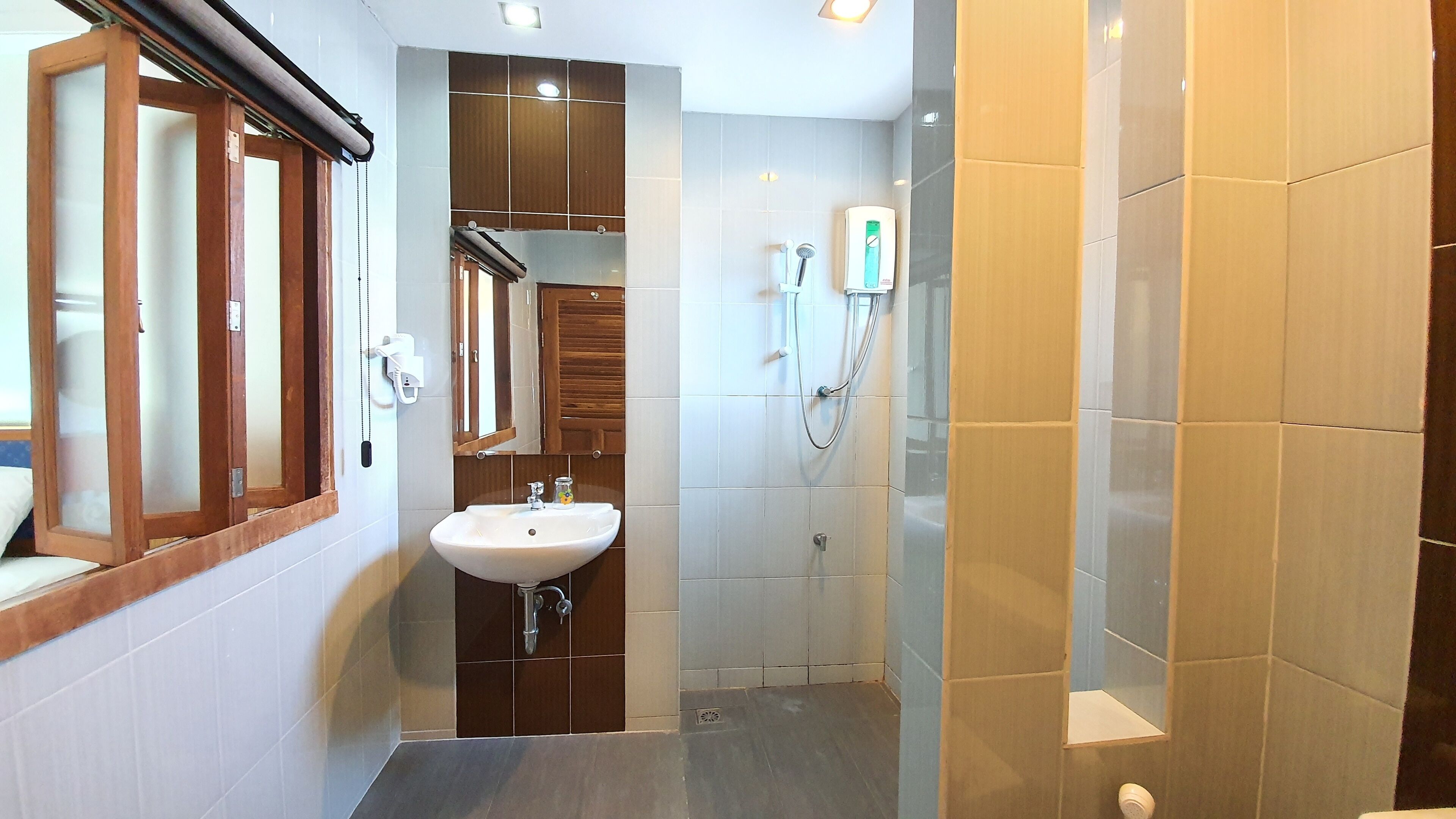 A compact bathroom with a sink, mirror, and shower.