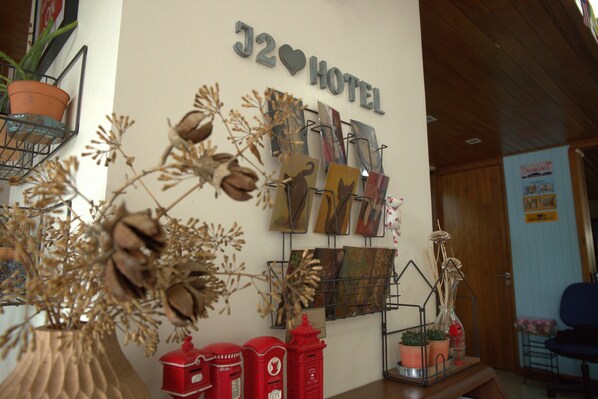 A hotel sign, a wall-mounted art display, and decorative items including potted plants and vintage mailboxes. - J2 Hotel (Mae Sot)