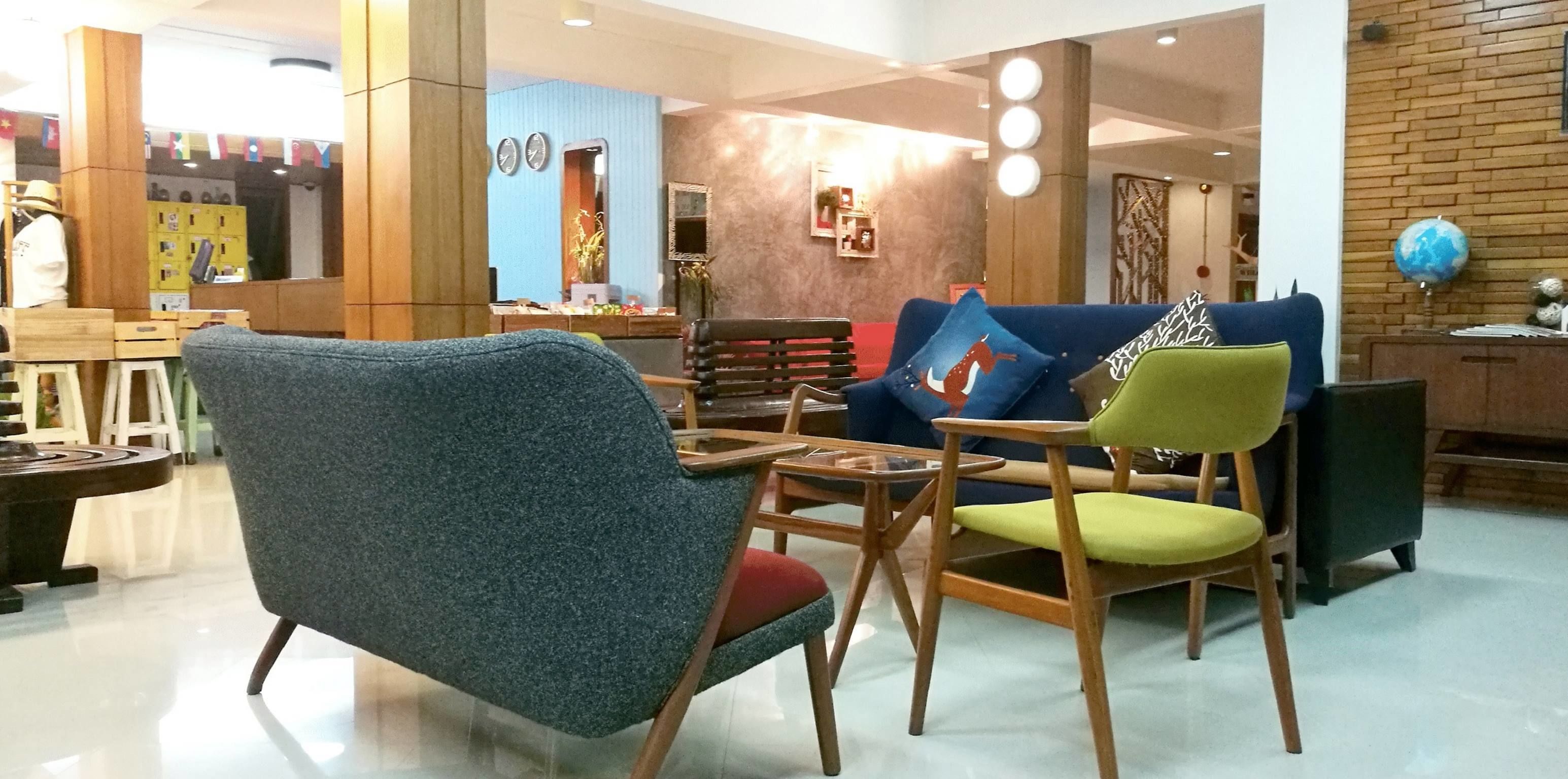 A modern hotel lobby with a blue sofa, wooden chairs, and a small table.